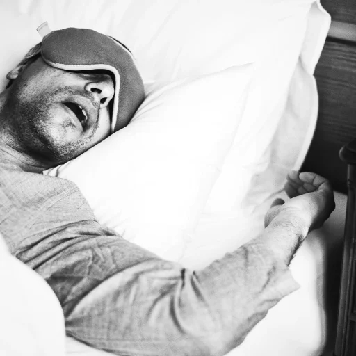 Homem dormindo com máscara de repouso, ilustrando ronco e apneia do sono
